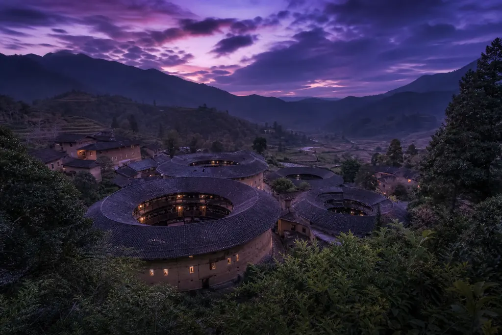 Casas redondas de tierra tulou de Fujian entre colinas verdes (imagen generada con AI)