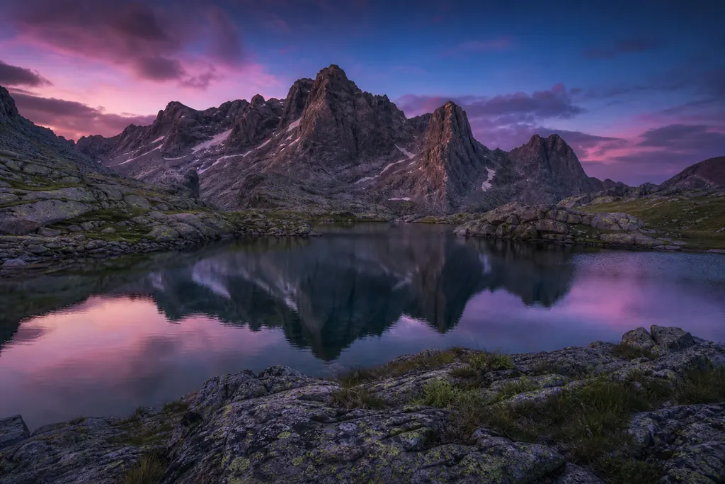 Picos de granito y una laguna de montaña en la sierra de Gredos al atardecer (imagen generada con AI)